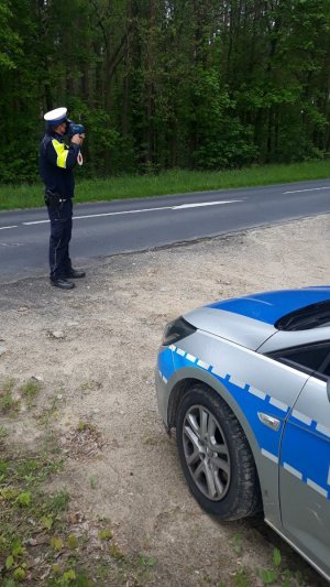 Policjant za pomocą urządzenia dokonuje pomiaru prędkości
