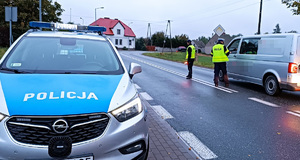 Jedna z kontrolowanych dróg na terenie powiatu sępoleńskiego. Policjant zatrzymuje pojazd aby zbadać trzeźwość kierowcy. Z boku drogi  stoi zapakowany radiowóz.